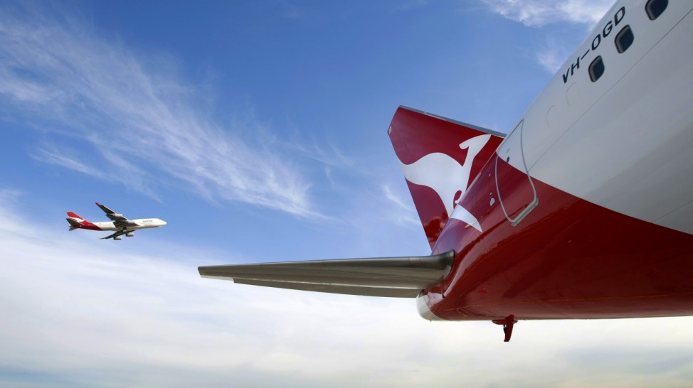 File photo of Qantas Boeing 747 flying past a 767 airplane with a newly unveiled Qantas logo on its tail in Sydney