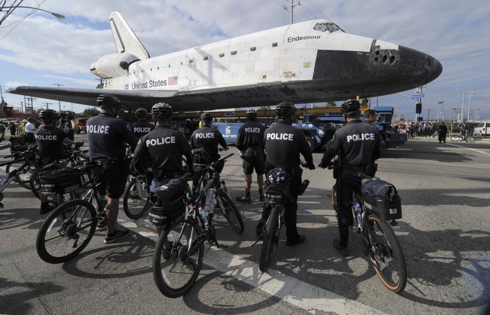 Policemen watch Space Space Shuttle Endeavour as it makes its way from Westchester square to Randy's Donuts during its final ground journey in Los Angeles