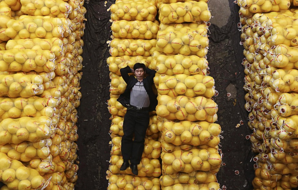 A vendor sleeps on packs of grapefruit at a market in Wuhan