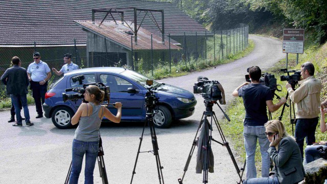 Members of the media gather next to a blocked road in Chevaline near Annecy, southeastern France