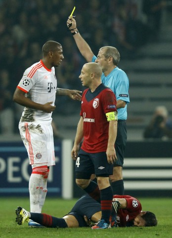 Referee Atkinson shows the yellow card to Bayern Munich's Boateng during their Champion's League Group F soccer match against Lille at the Lille Grand Stade stadium in Villeneuve d'Ascq