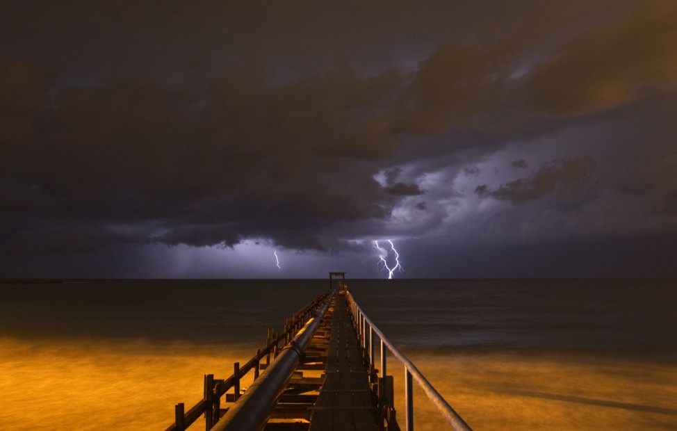 Lightning strikes over a pier during a storm in Atlit