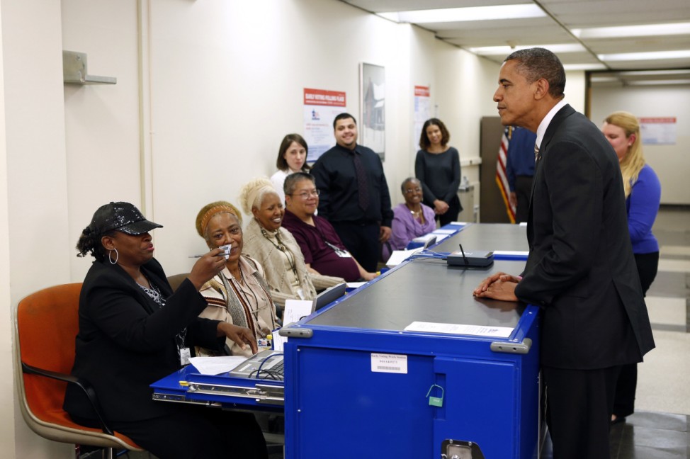 Polling workers double check the photo on U.S. President Barack Obama's drivers license as he voted early at the Martin Luther King Community Center in Chicago