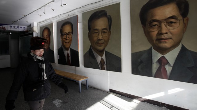 Ein Mann läuft an Porträts von Wen Jiabao, Hu Jintao  und ehemaligen Machthabern Chinas vorbei