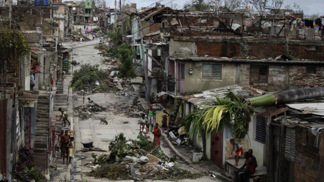 People walk on a street littered with debris after Hurricane Sandy hit Santiago de Cuba
