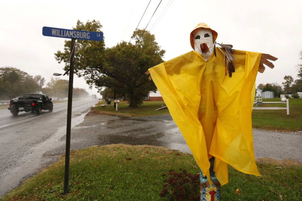 Vehicles pass a Halloween scarecrow fitted with a rain poncho as Hurricane Sandy hits Easton, Maryland