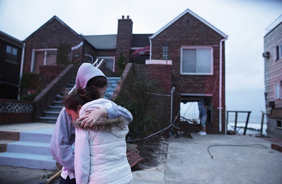 Deoadato and Denino hug in front of their aunt's house destroyed by rising waters from last night's storm surge due to Hurricane Sandy in New York