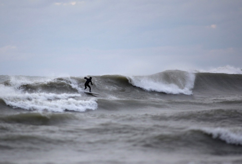 Surfers endure the cold waters as large surf batters the Milwaukee coastline from the long reaching effects from Hurricane Sandy