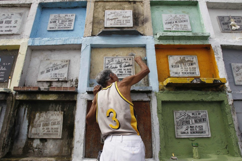 A man applies paint on his relatives Apartment Style tomb at a public cemetery in Malabon city