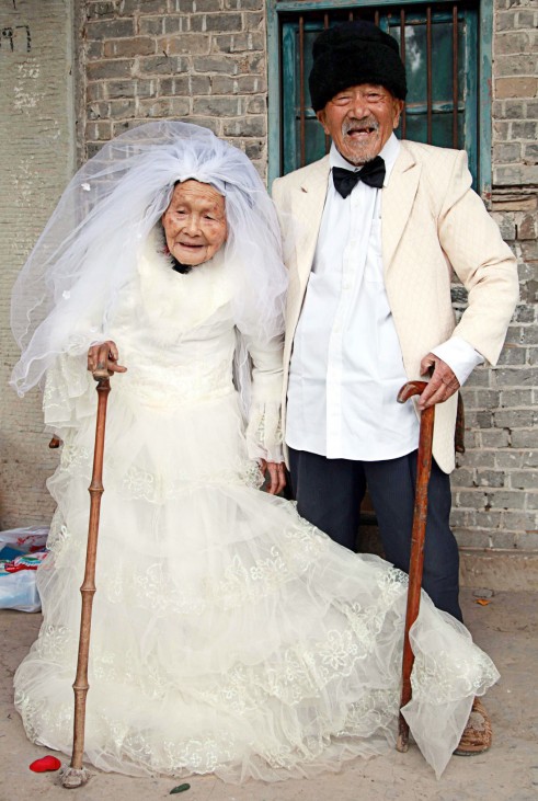 Wu Conghan, 101 years old, and his 103-year-old wife pose for photos while wearing wedding clothes at their home in a village of Nanchong