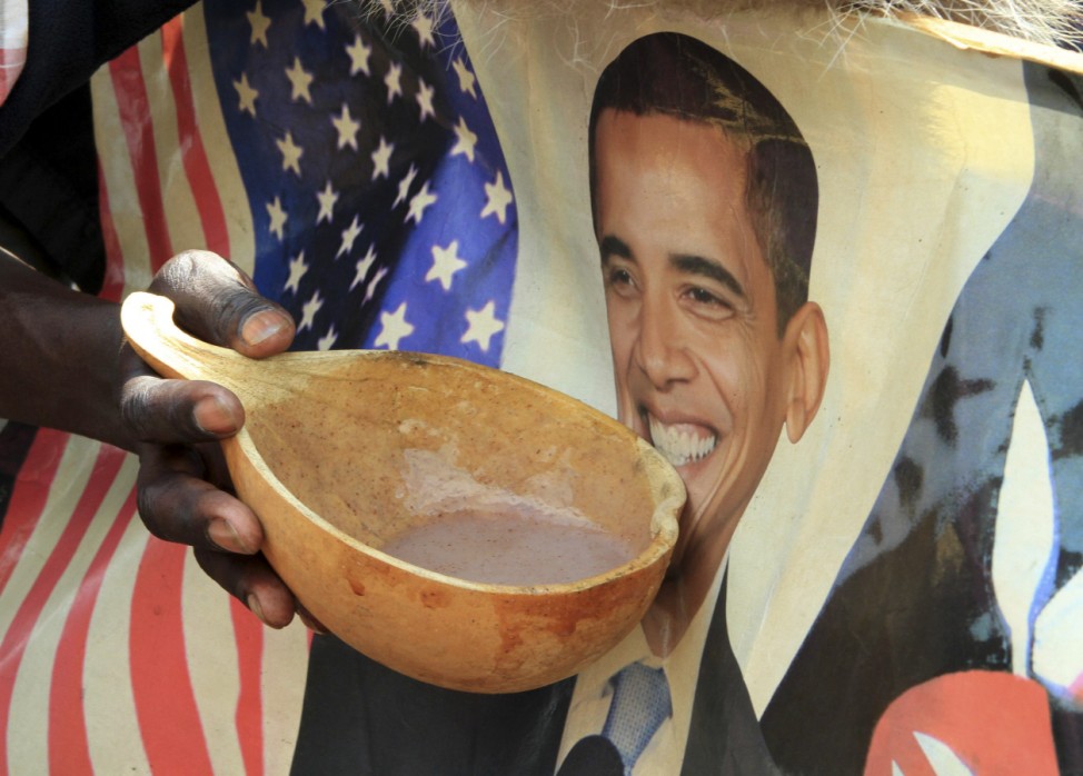 A person holds a bowl of local porridge against a poster of U.S. President Barack Obama as they celebrate his re-election in the sprawling Kibera slums of Kenya's capital Nairobi