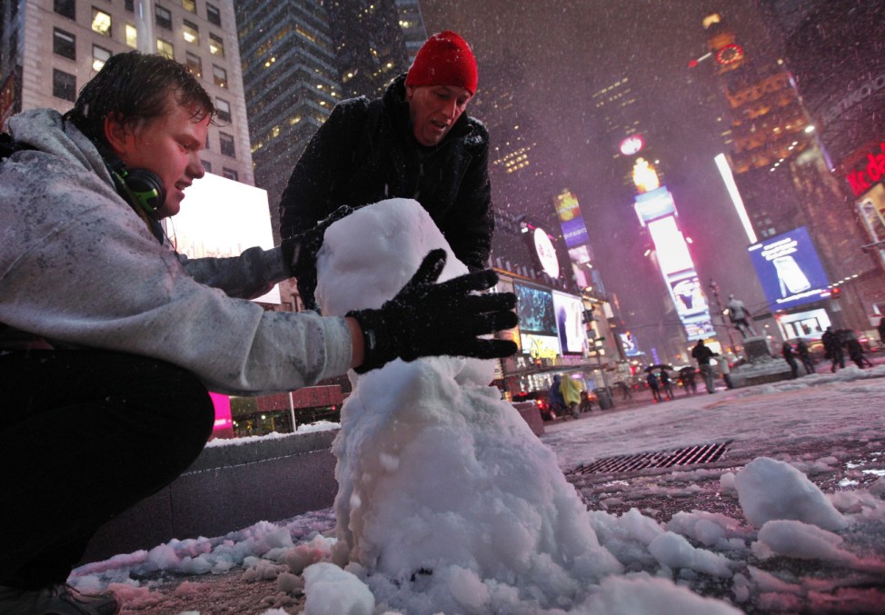 Henrik from Norway and John from Wayne, New Jersey build a snowman together during a snow storm in New York's Times Square