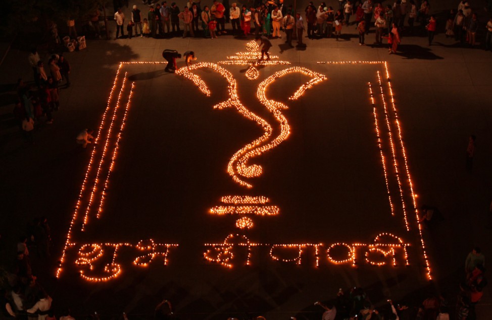 People light earthen lamps in a formation to form the shape of Hindu god Ganesh on the eve of Diwali in Chandigarh