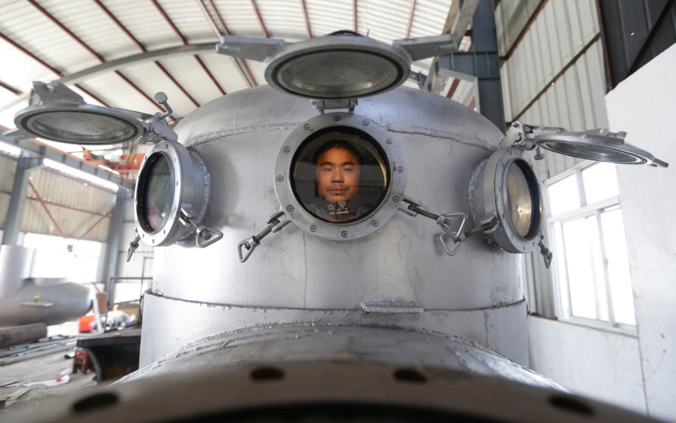Zhang Wuyi sits in his newly made multi-seater submarine at his new workshop near an artificial pool in Wuhan