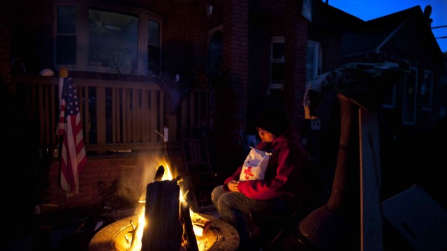 Handout of Mendez warms up by a fire outside her heavily devastated home in Staten Island, New York