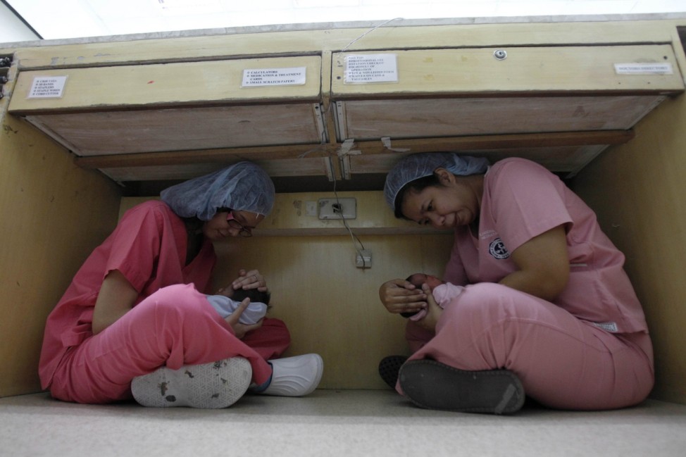 Nurses carry newborn babies as they take cover under a table during an earthquake drill at Manila Doctors Hospital in Manila