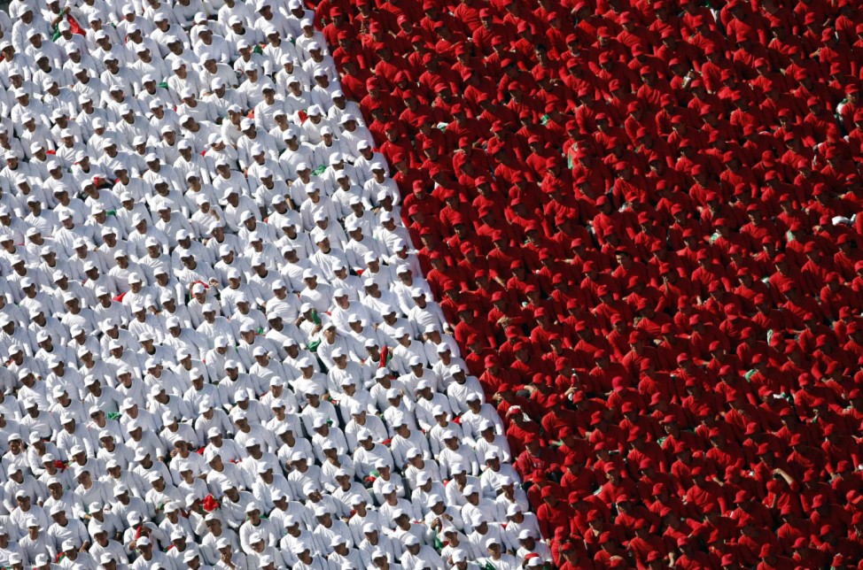 People wearing white and red costumes sit in grandstand during celebration of 102nd anniversary of Mexican Revolution on Zocalo Square in Mexico City