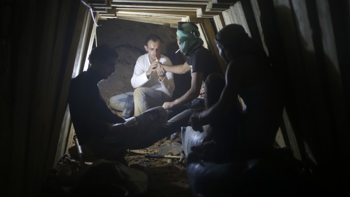 Palestinians smoke cigarettes as they work inside a smuggling tunnel dug beneath the Egyptian-Gaza border in the southern Gaza Strip