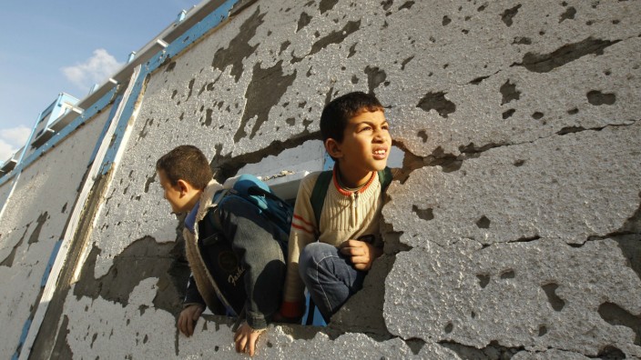 Die besten Blogs: Palästinensische Schulkinder schauen durch ein Loch einer zerbombten Mauer.