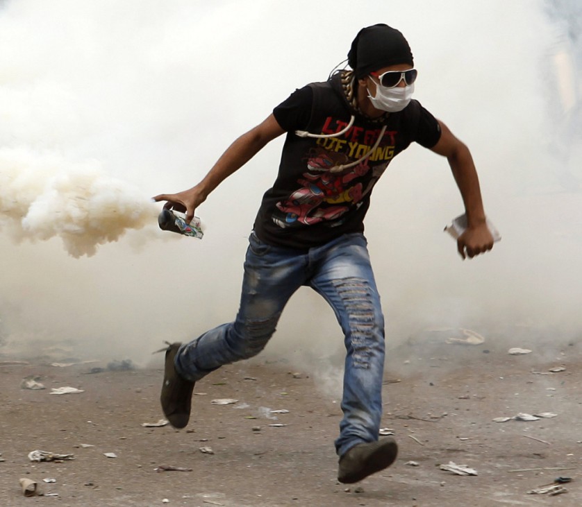 Protester runs to throw tear gas canister back at police during clashes near Tahrir Square in Cairo