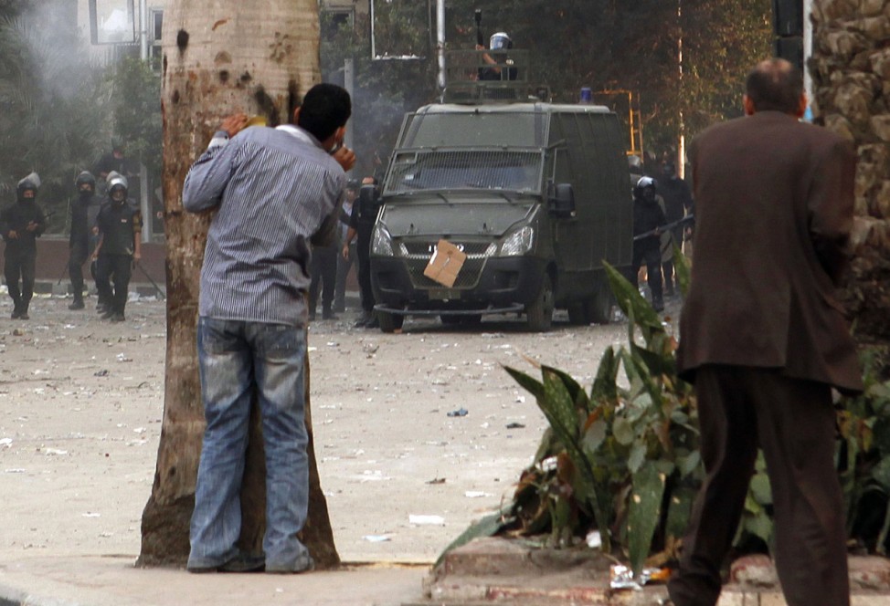Protesters hide from police during clashes near Tahrir Square in Cairo
