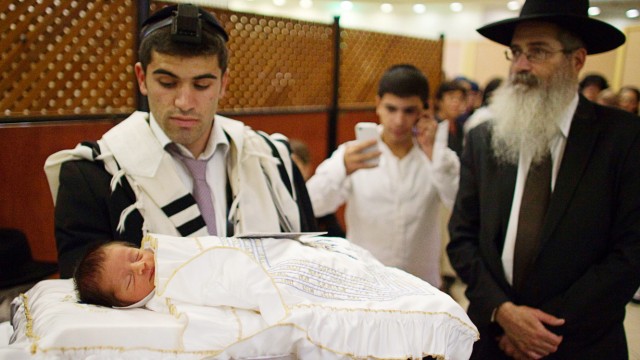 File photo of Jewish man holding his baby son before his circumcision in Jerusalem
