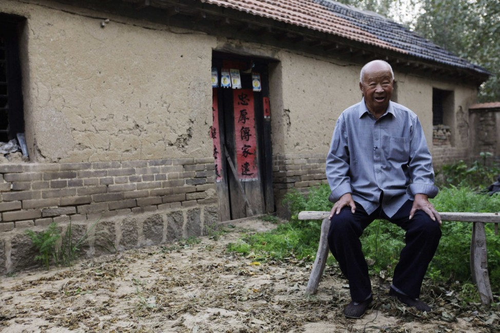 The father of Chinese writer Mo Yan smiles during an interview with Reuters in front of Mo's childhood home at Pinganzhuang village