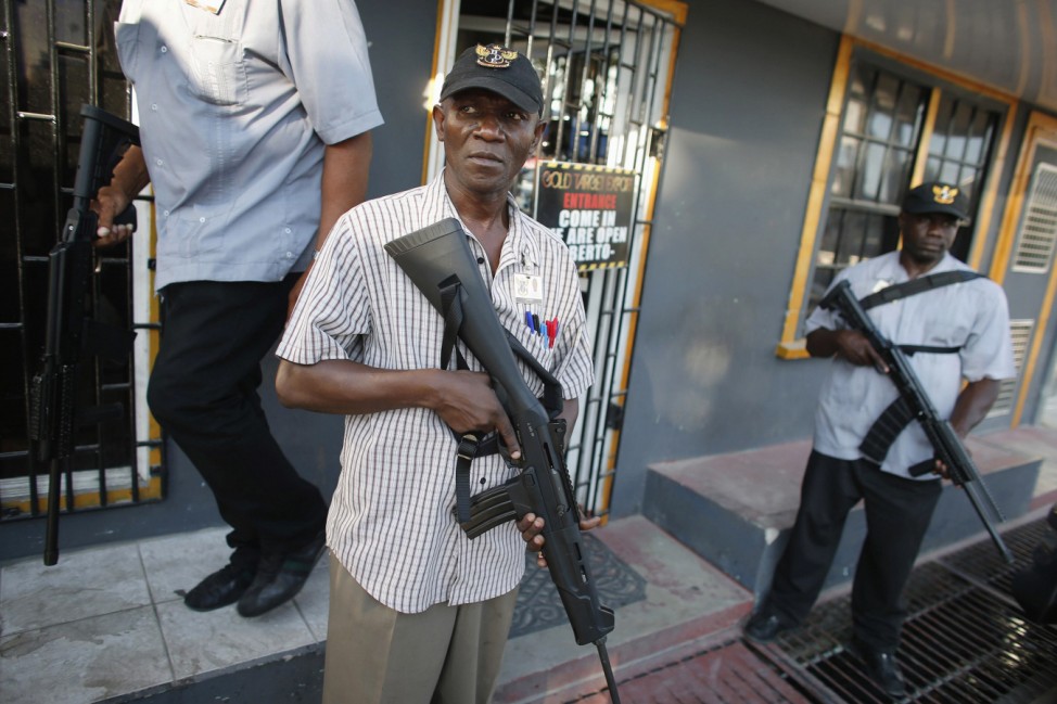 Heavily armed guards hold their weapons outside a business licensed to buy rough diamonds and gold in Georgetown