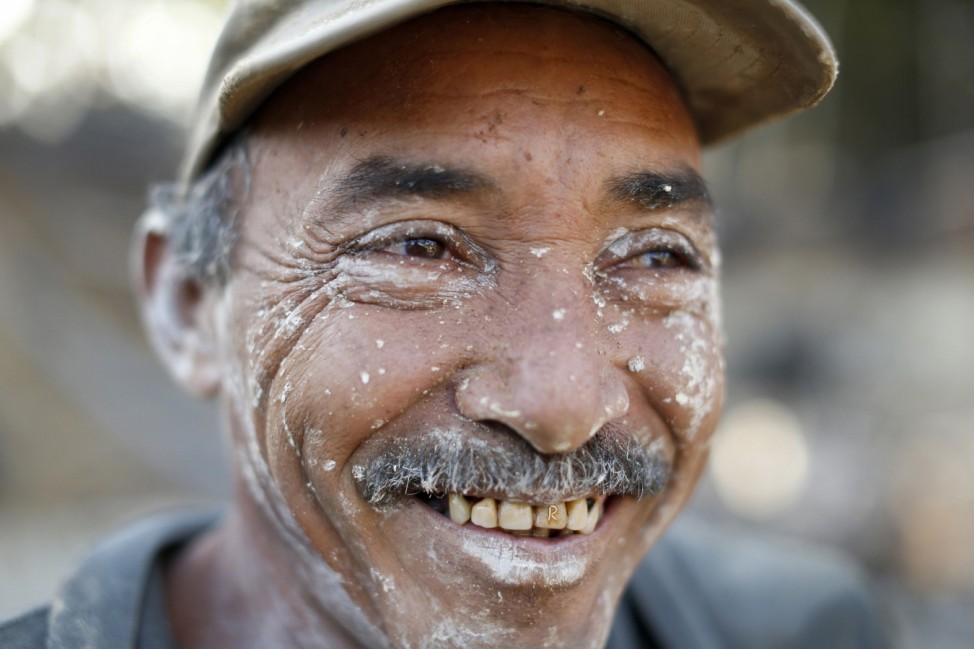 An miner named Ramon flashes a gold letter 'R' on his tooth as he smiles after working in a mine in the southern state of Bolivar