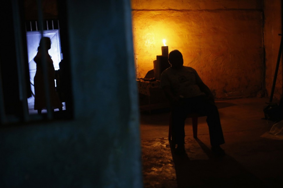 A miner, illuminated by the light of a candle, sits in his house at night in the miner's town Ikabaru