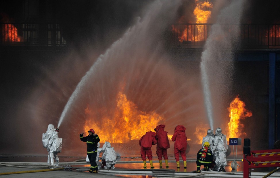 Firefighters practice during a chemical plant fire protection drill at a firefighter training base in Chongqing Municipality
