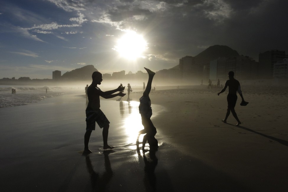 A boy does a headstand at sunset on Copacabana Beach in Rio de Janeiro