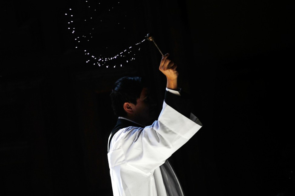 A priest throws blessed water at Basilica's square during celebrations marking the Day of the Virgin of Guadalupe in Mexico City