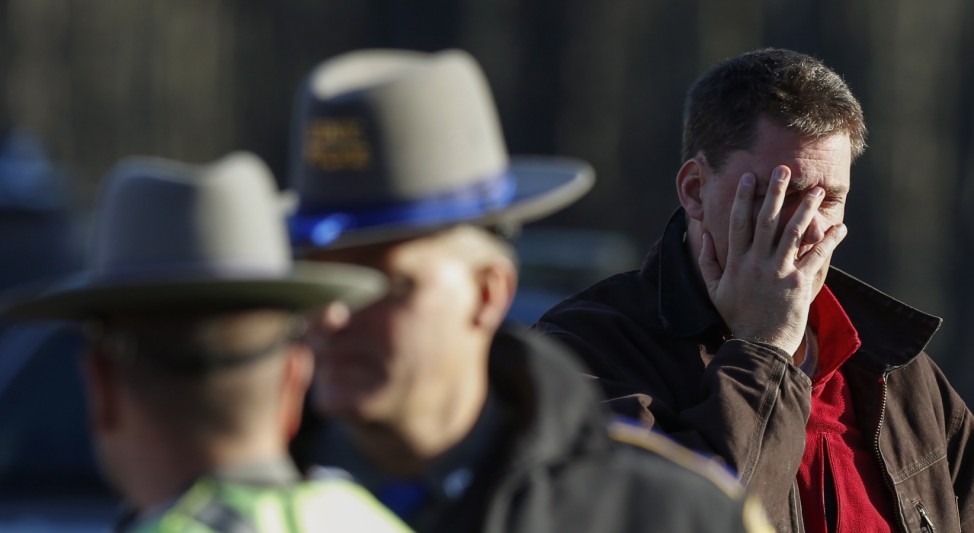 A man grieves next to police staged at the site of a shooting near Sandy Hook Elementary School were a gunman opened fire on school children and staff in Newtown, Connecticut