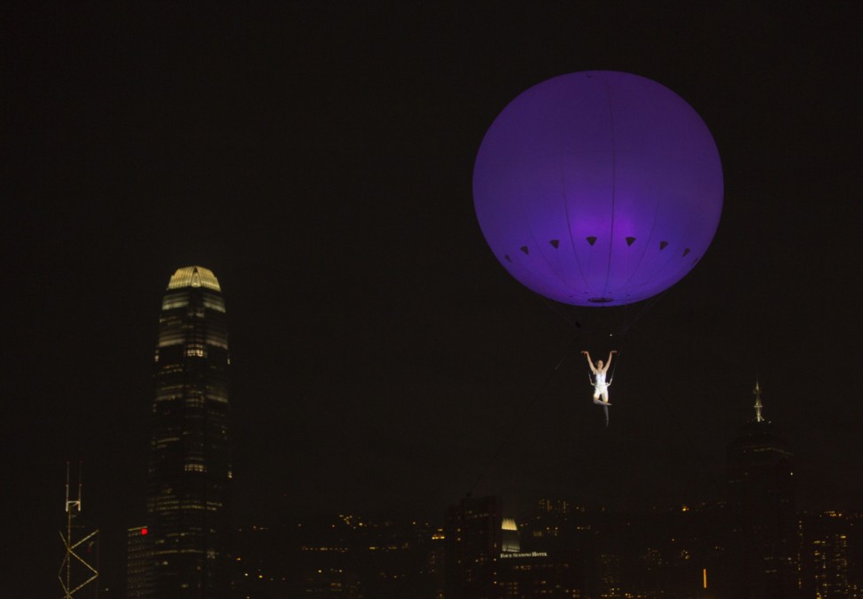 Dancer of London's the Dream Engine performs under the heliosphere, a massive helium balloon, with the backdrop of Hong Kong's skyline