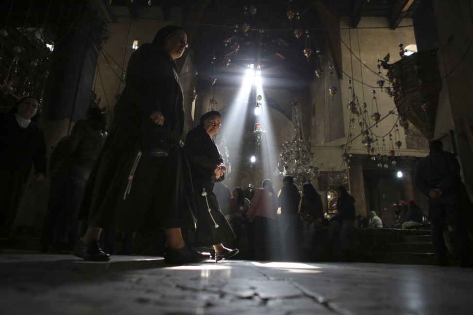 Nuns walk past worshippers in the Church of the Nativity in Bethlehem