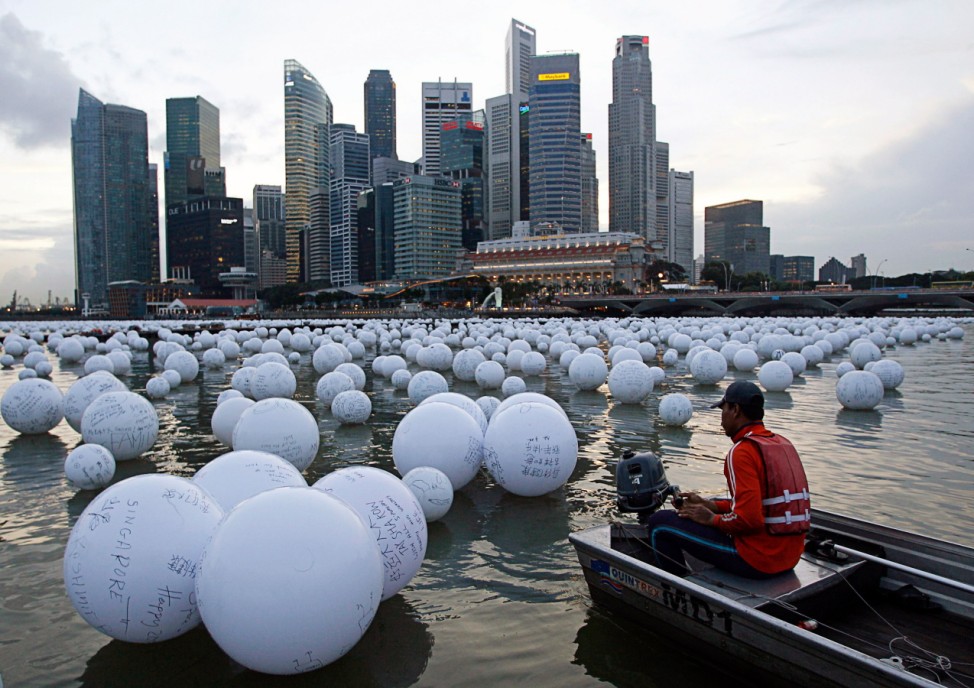 A boatman arranges wishing spheres floating on the Singapore river