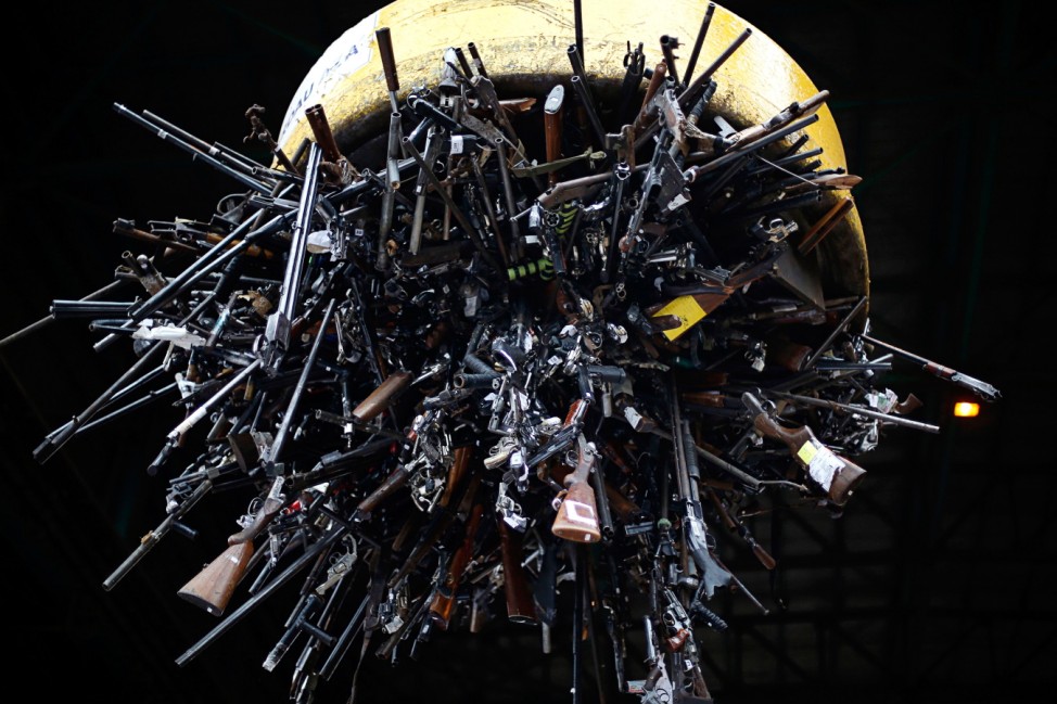 Confiscated weapons hang from a magnet before being destroyed at a foundry in Santiago