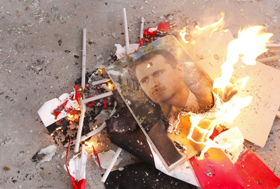 Pictures of Syria's President Bashar al-Assad and Syrian flags burn after being set on fire by Free Syrian Army fighters in Ouwayjah village in Aleppo