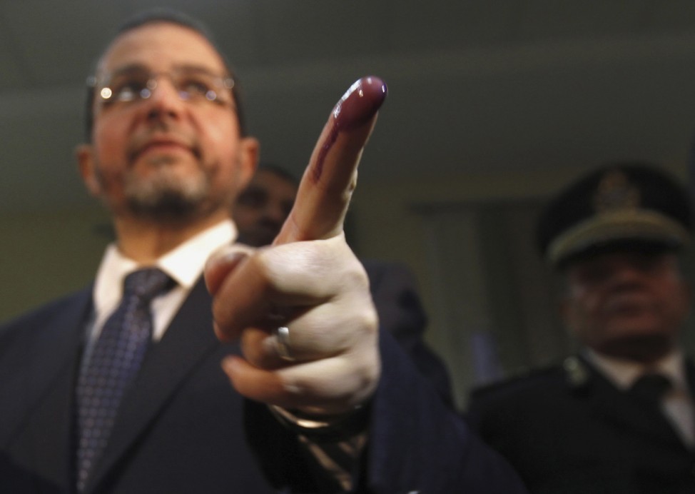Egypt's Prime Minister Hisham Qandil shows his ink-stained finger after casting his vote in the final stage of a referendum on Egypt's new constitution in El Dokki district of greater Giza, south of Cairo