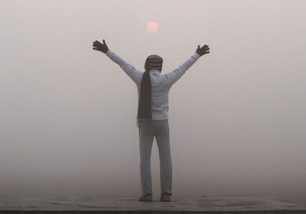A man exercises as the sun rises amid dense fog on a cold winter morning in Kolkata