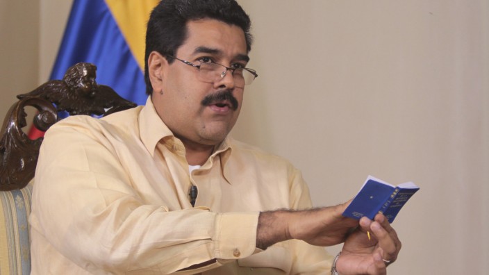 Venezuela's Vice President Nicolas Maduro speaks while holding a copy of his country's constitution during an interview in Caracas