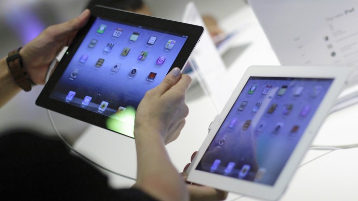A couple compares an Apple third generation iPad to an iPad 2 on display at an Apple reseller store in Singapore