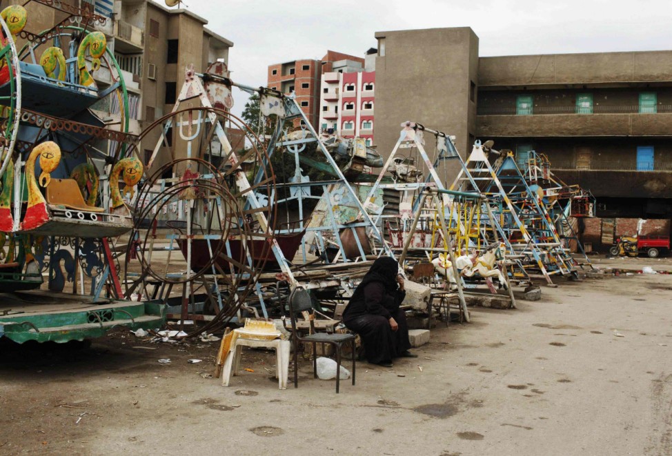 A woman waits for customers in front of a funfair in the Egyptian Delta town of Zagazig
