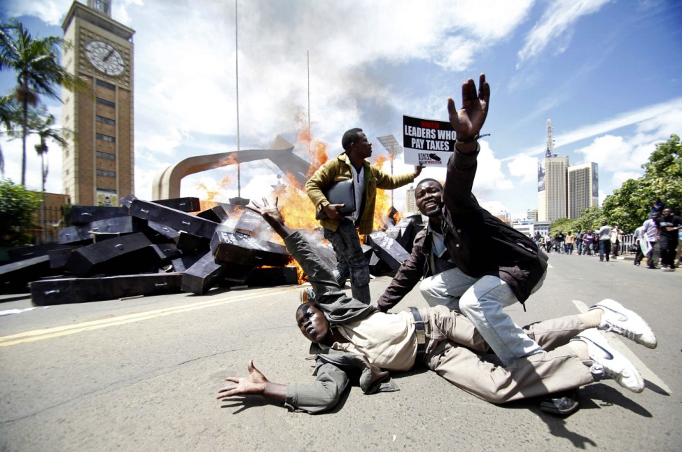 Activists react as mock coffins burn outside the Kenyan parliament during a protest in Nairobi