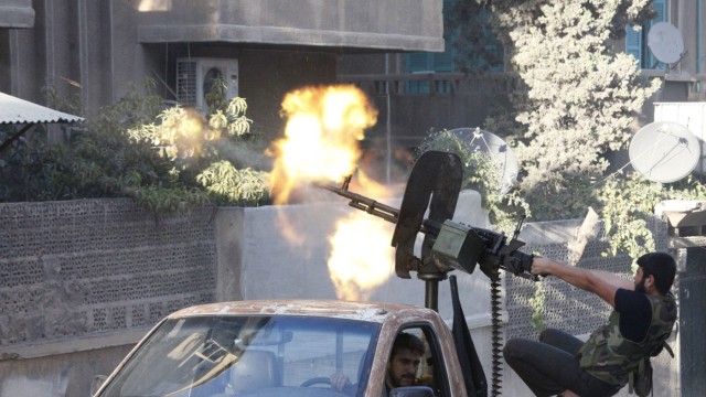 A member of Free Syrian Army open fire from his machine gun during clashes with Syrian Army forces in Aleppo