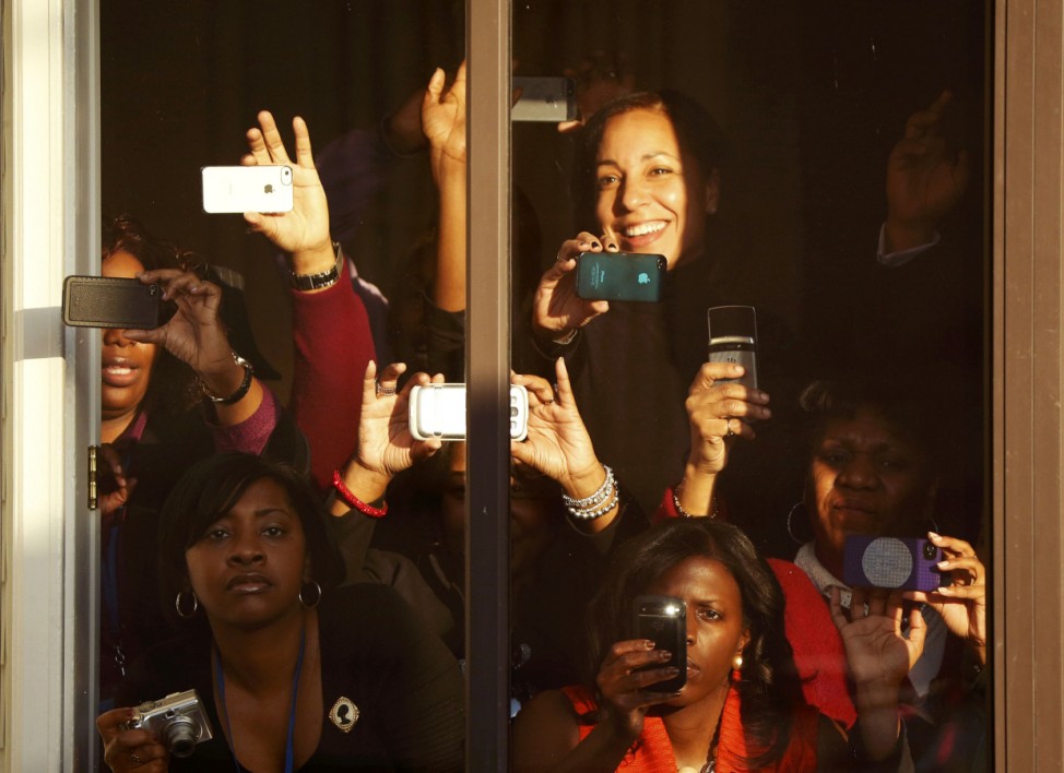 Spectators take photos from a window as they watch U.S. President Barack Obama during the inaugural parade in Washington