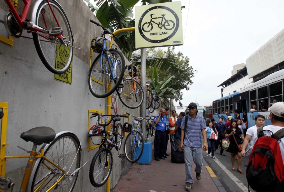 Commuters walk past bicycles for rent along a main street in Makati city