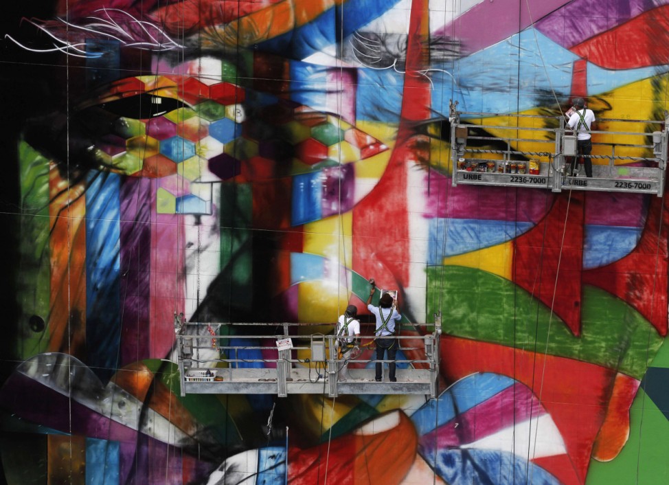 Brazilian graffiti artist Kobra puts the final touches to his piece of art in tribute to Brazilian architect Niemeyer, next to his assistants, at the financial center in Sao Paulo