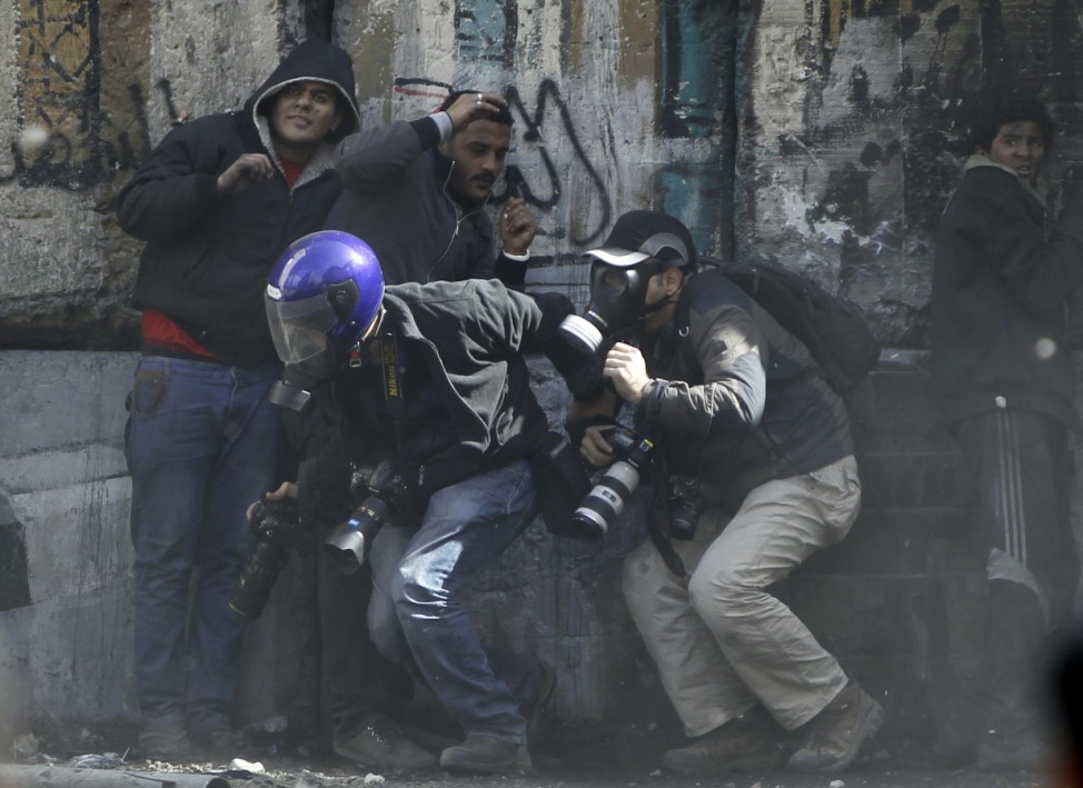 Photographers cower as protesters throw stones towards riot police along Sheikh Rihan street near Tahrir Square in Cairo